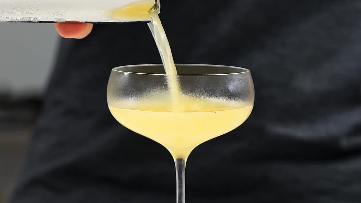 Straining Corpse Reviver No 2 into a chilled cocktail glass