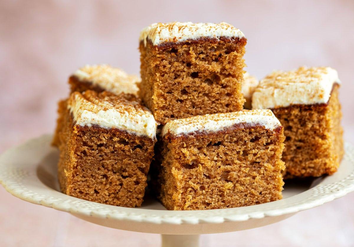 Air fryer apple cake with cream cheese frosting, square pieces piled on a cake stand