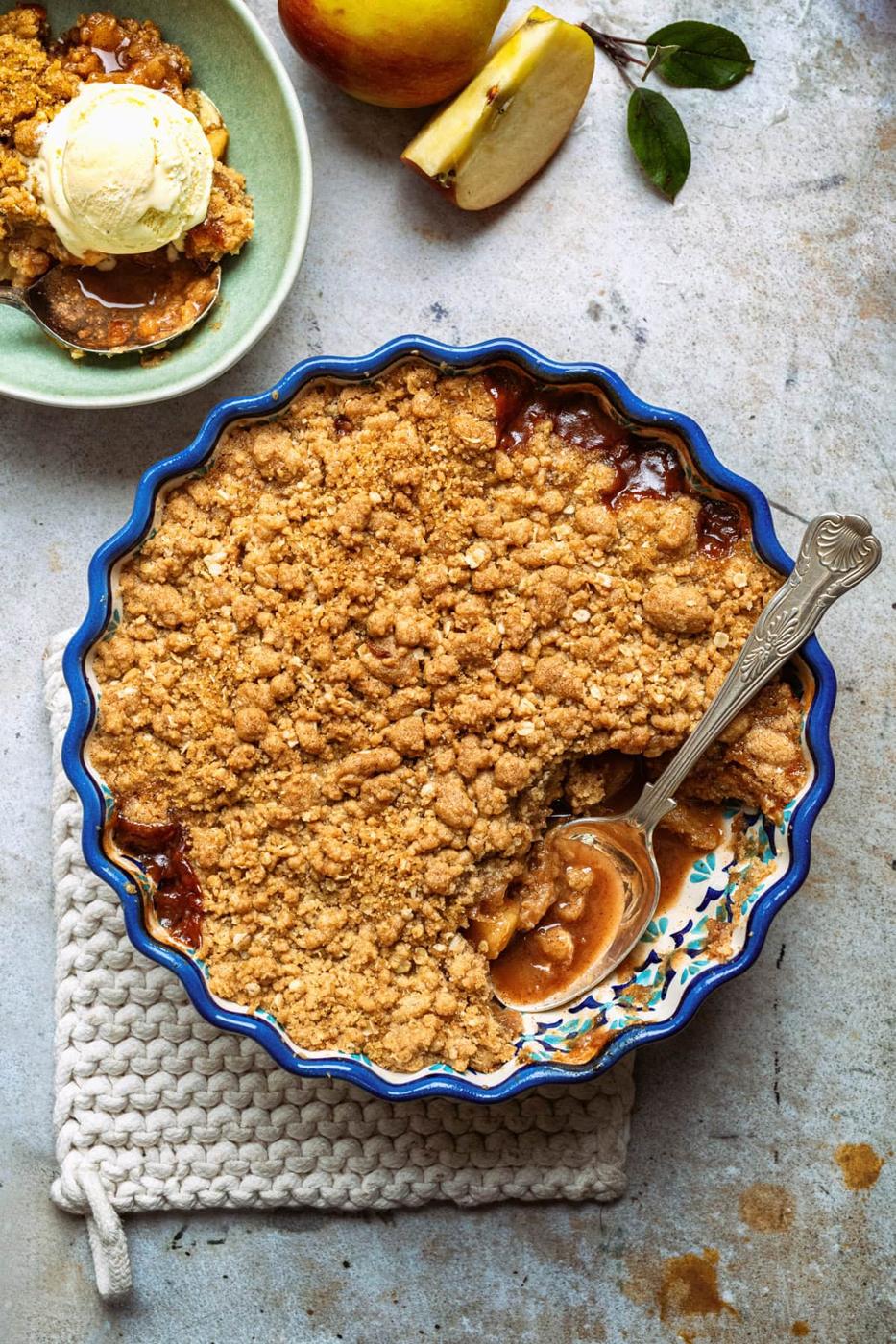 Air Fryer apple crumble in a pie dish, bowl serving and apples on the side