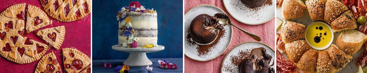 Four desserts: heart-cut pie slices, flower-topped white cake, two plates of chocolate lava cake with spoons, and a round bread wreath with dipping sauce, meats, and olives on a pink tablecloth.