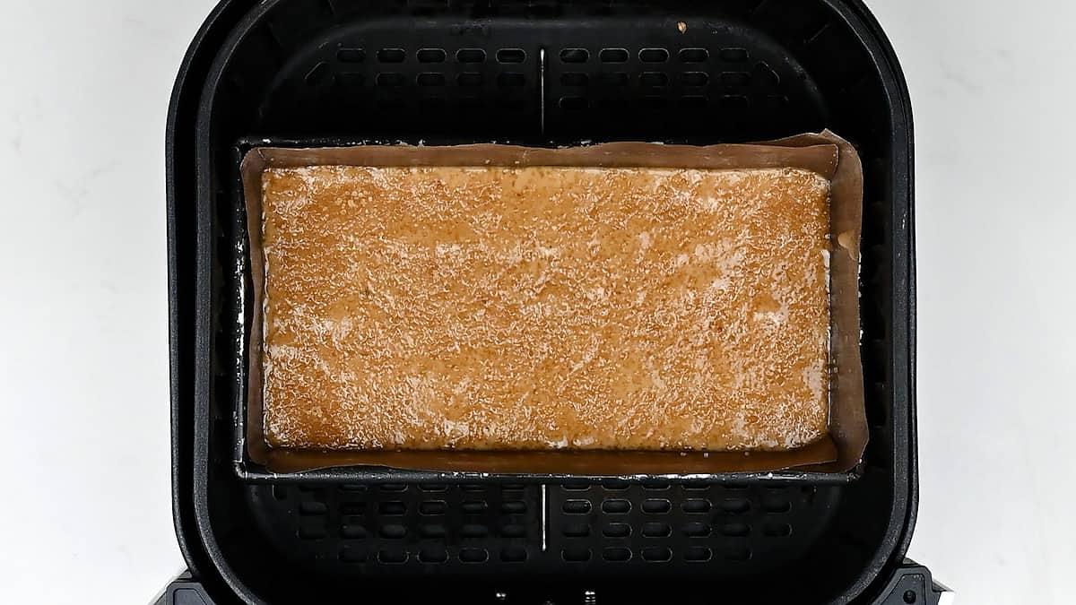 Loaf tin filled with banana bread batter in an air fryer basket