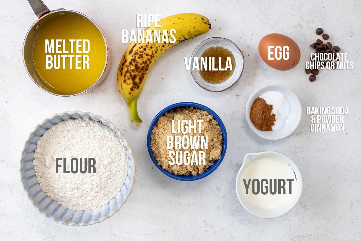 Top-down view of ingredients for Banana Bread Muffins: melted butter, ripe banana, vanilla, egg, chocolate chips or nuts, flour, light brown sugar, yogurt, and a mix of baking soda, baking powder, and cinnamon—perfect for your Air Fryer.