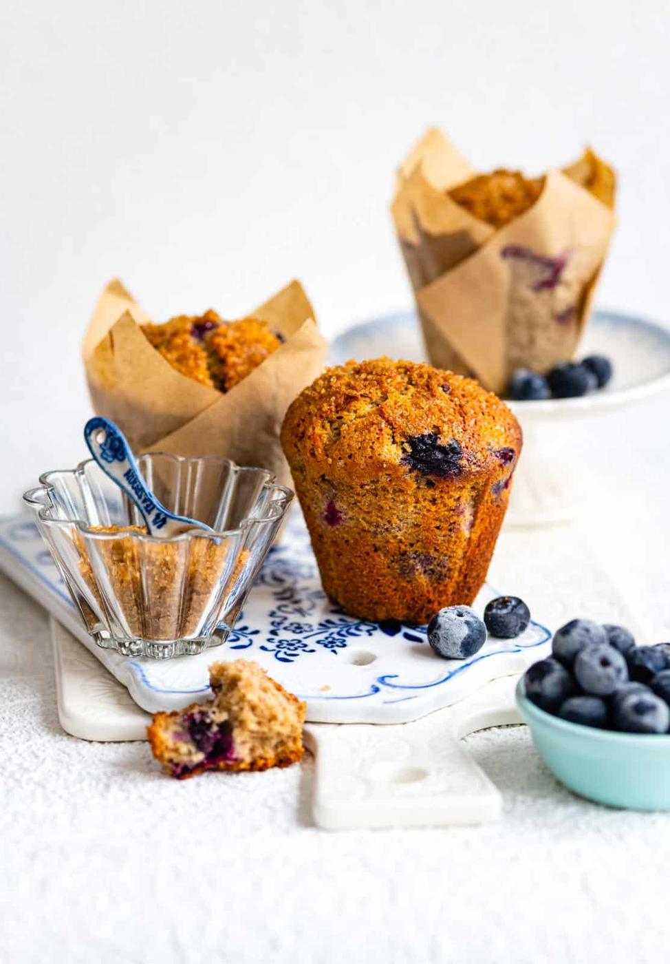 Blueberry muffins with blueberries on the side on white background