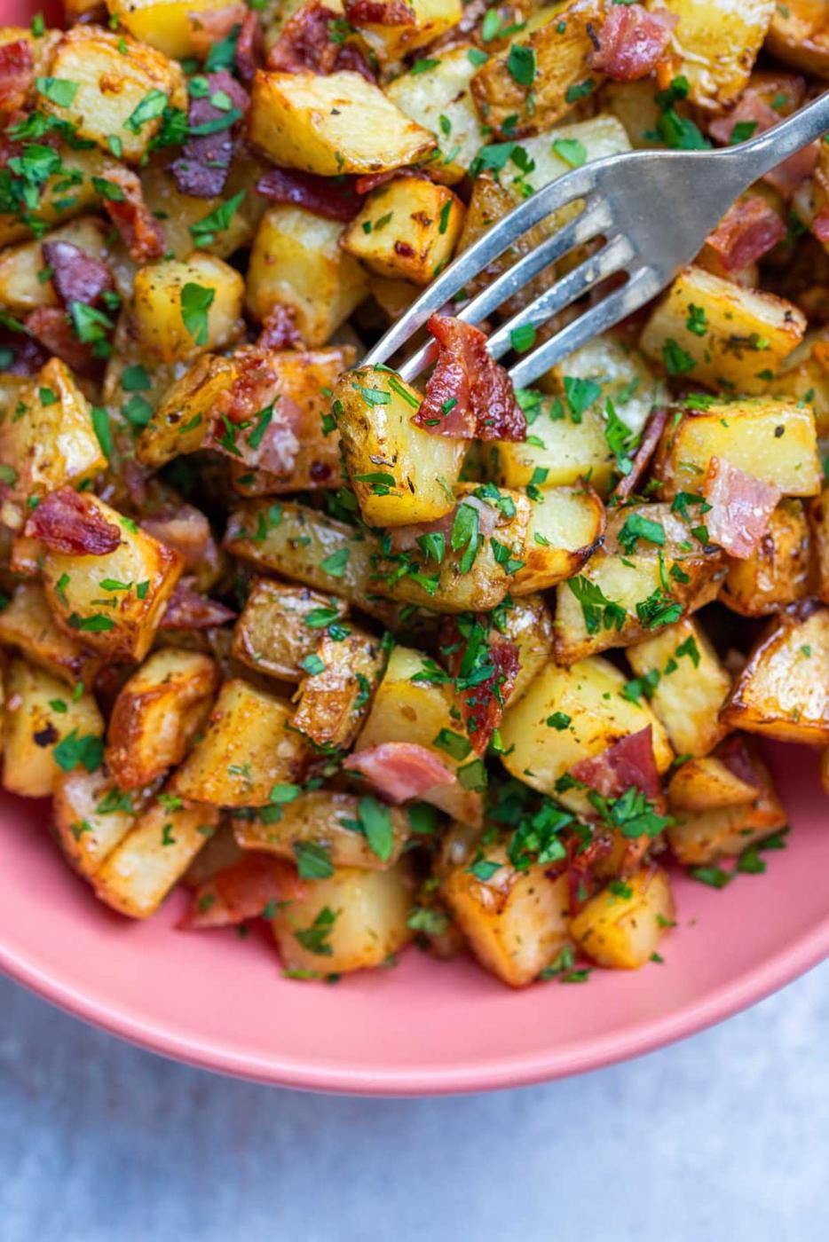crisp air fryer breakfast potatoes with honey and bacon in a bowl, fork piercing one