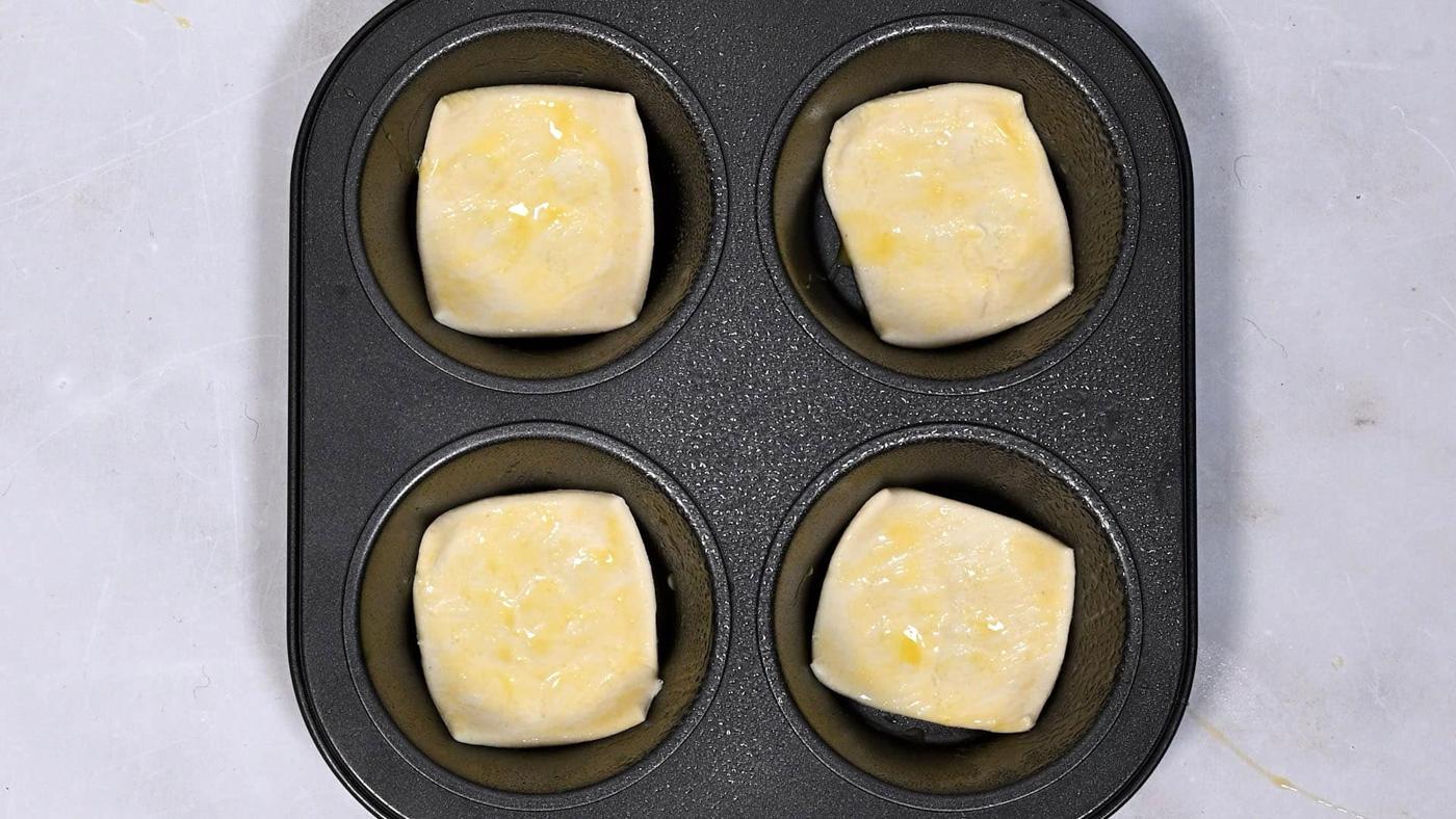 puff pastry squares in a small muffin tray brushed with egg wash