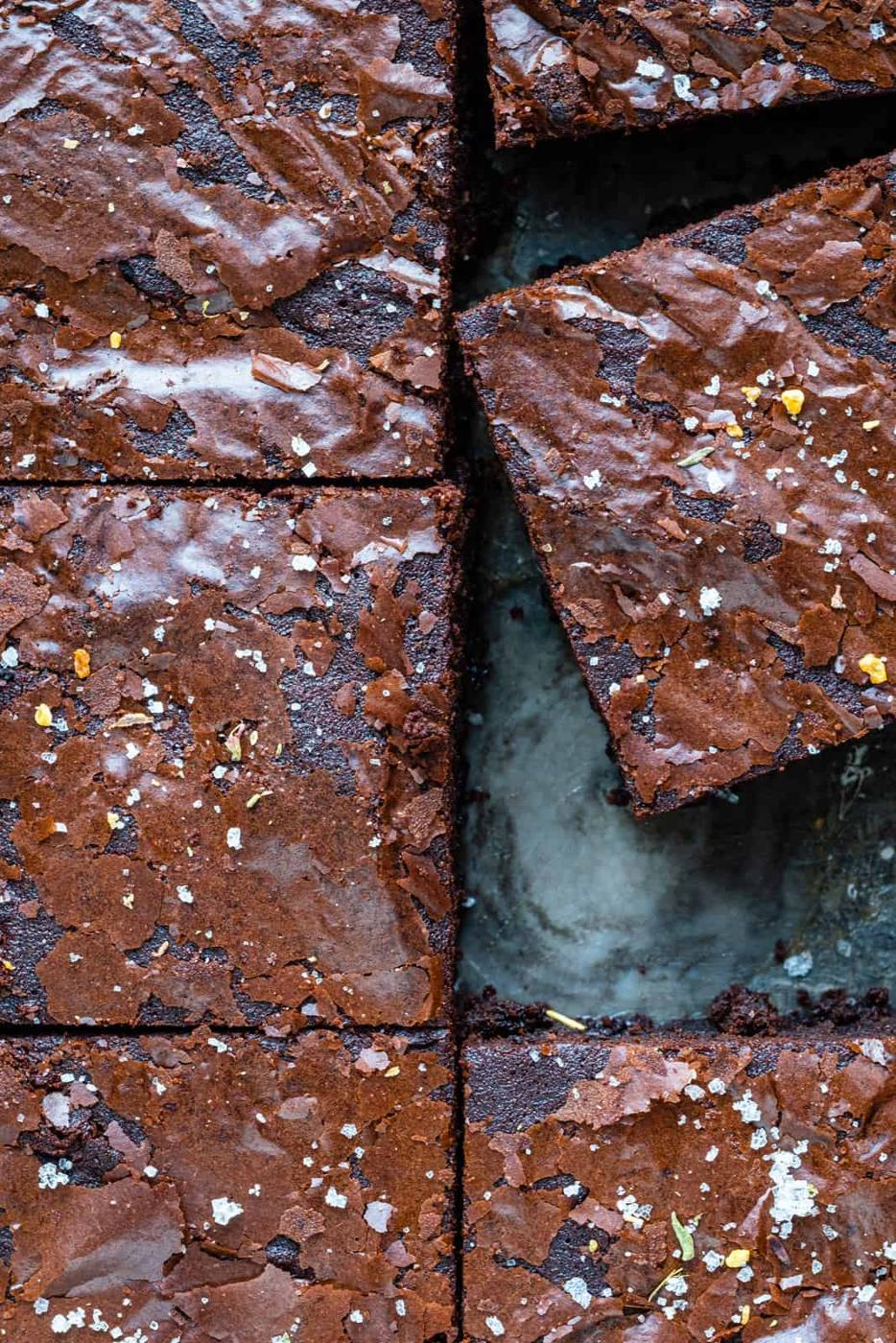Close-up of sliced Air Fryer Brownies with a shiny, crackly top, sprinkled with flaky sea salt. One brownie is slightly lifted, revealing the soft, fudgy interior and rich chocolate texture you get from brownies in an air fryer.