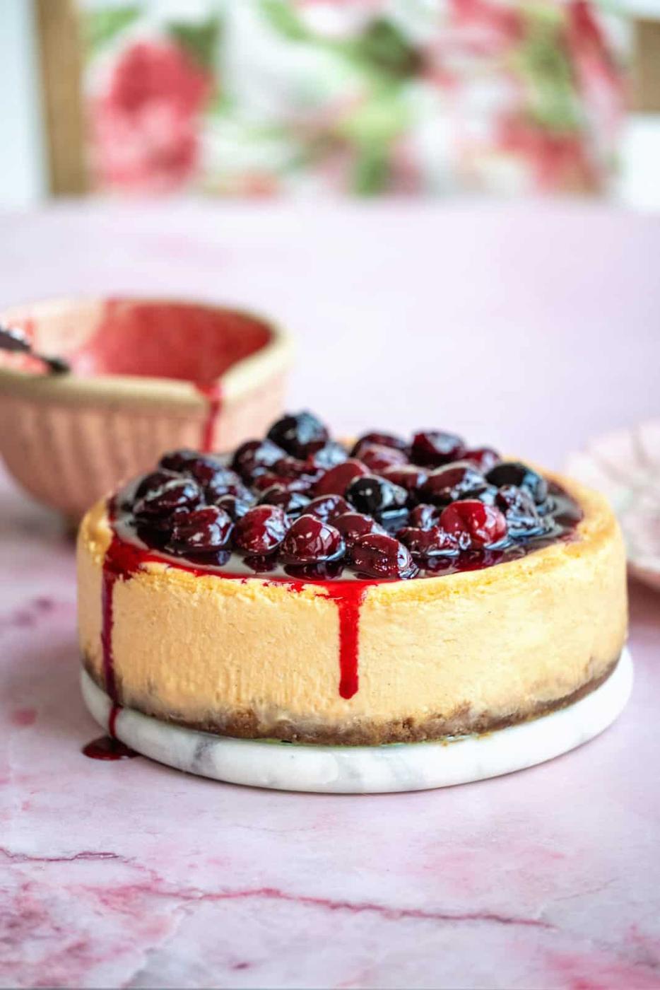 Air Fryer Cheesecake topped with cherries on a marble board