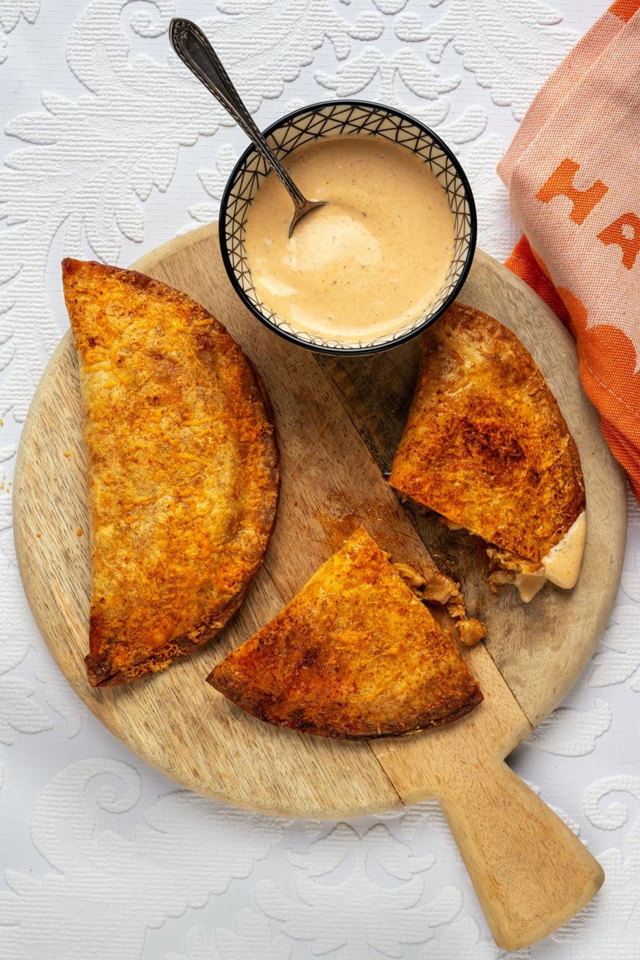 Taco Bell copycat chicken crispanadas on a wooden board with a bowl of spicy ranch dip on the side