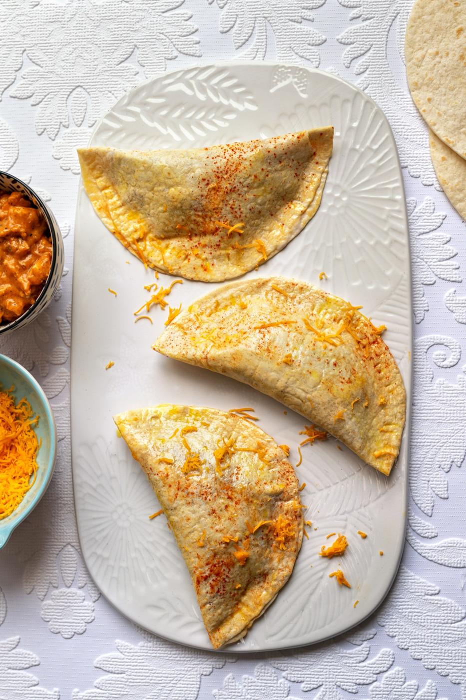 three Crispanadas prior to cooking on a white ceramic board