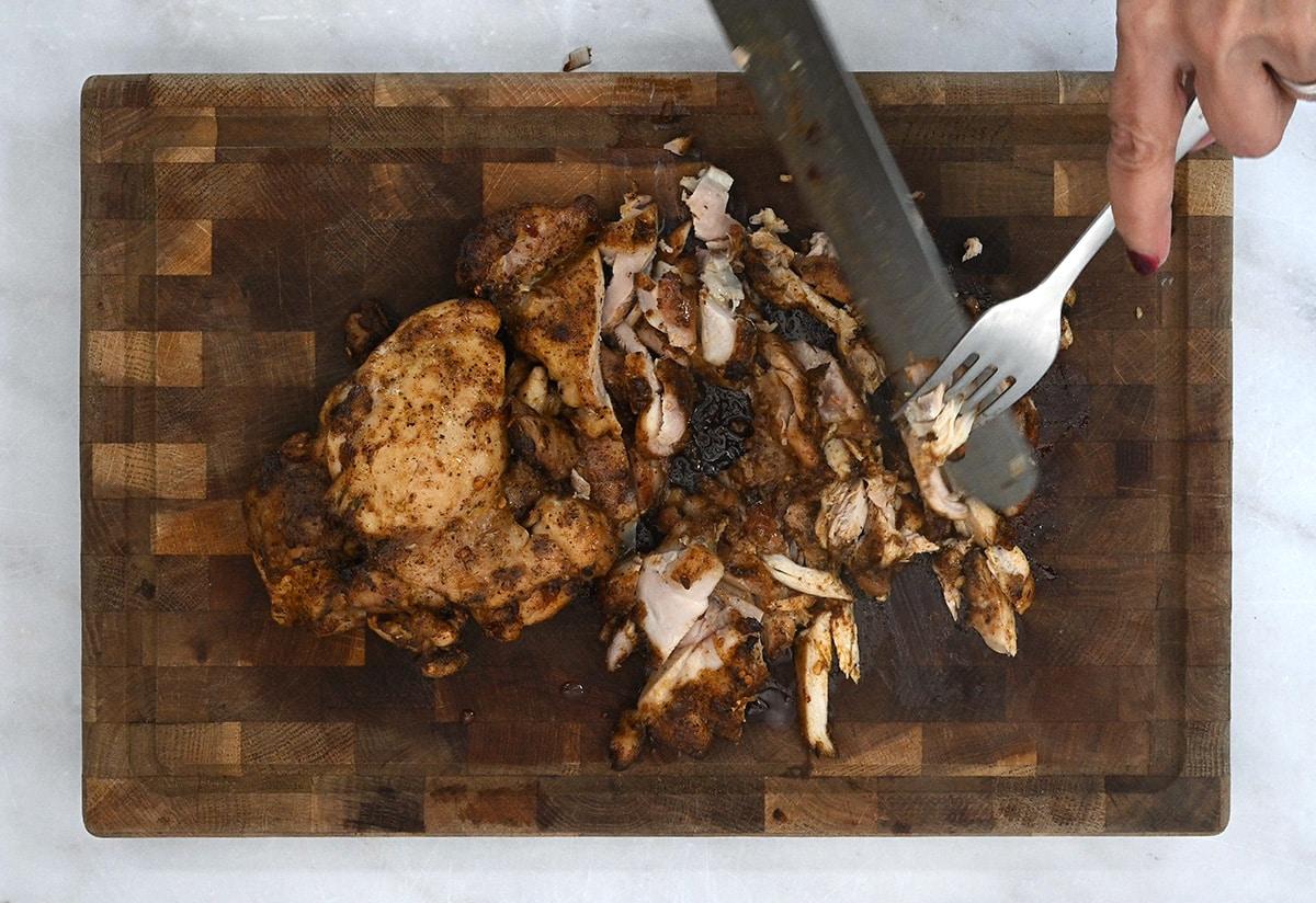 slicing chicken thighs on a board