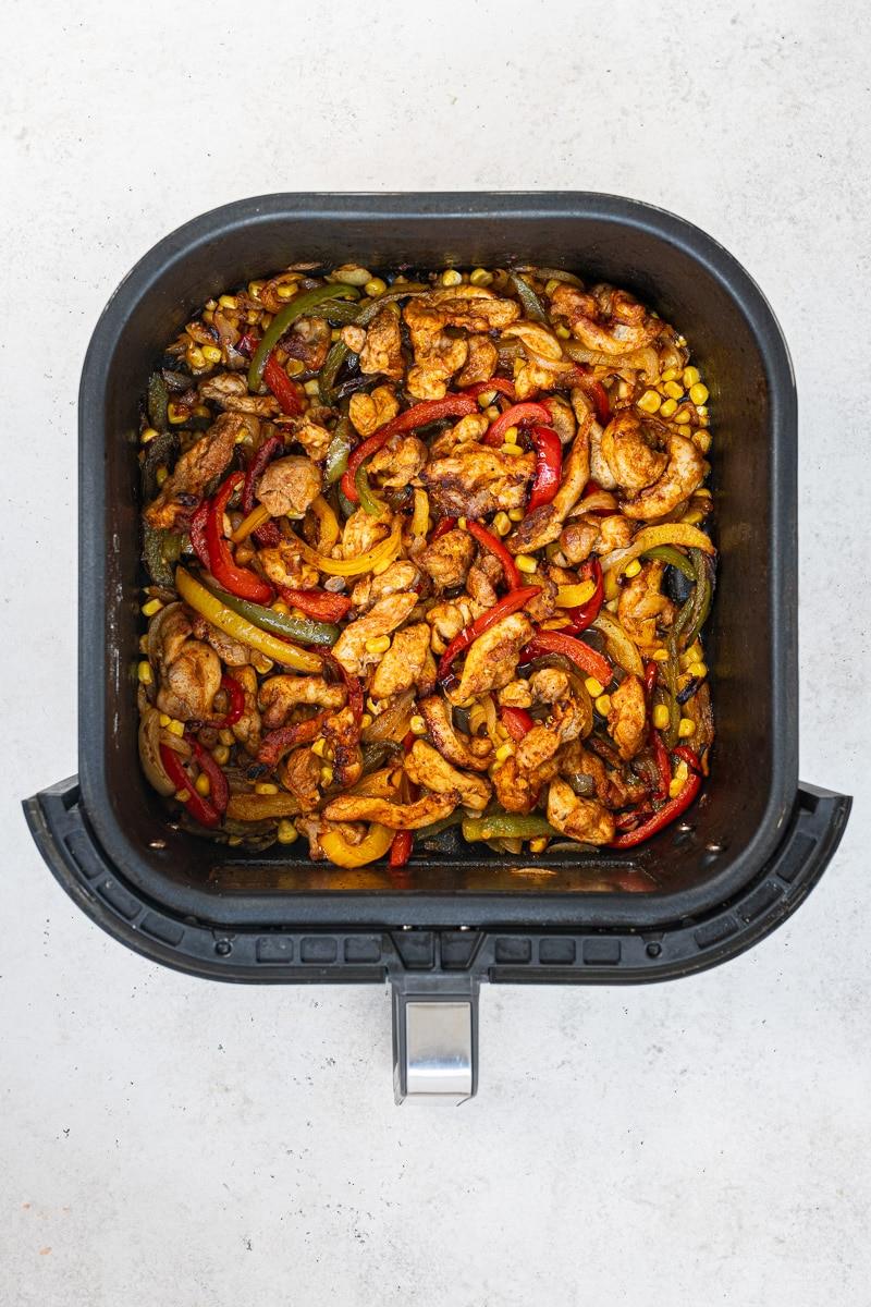 overhead view of cooked chicken fajitas, in an air fryer basket