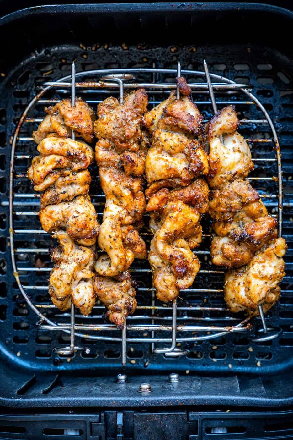 Chicken souvlaki skewers in the air fryer basket on a rack
