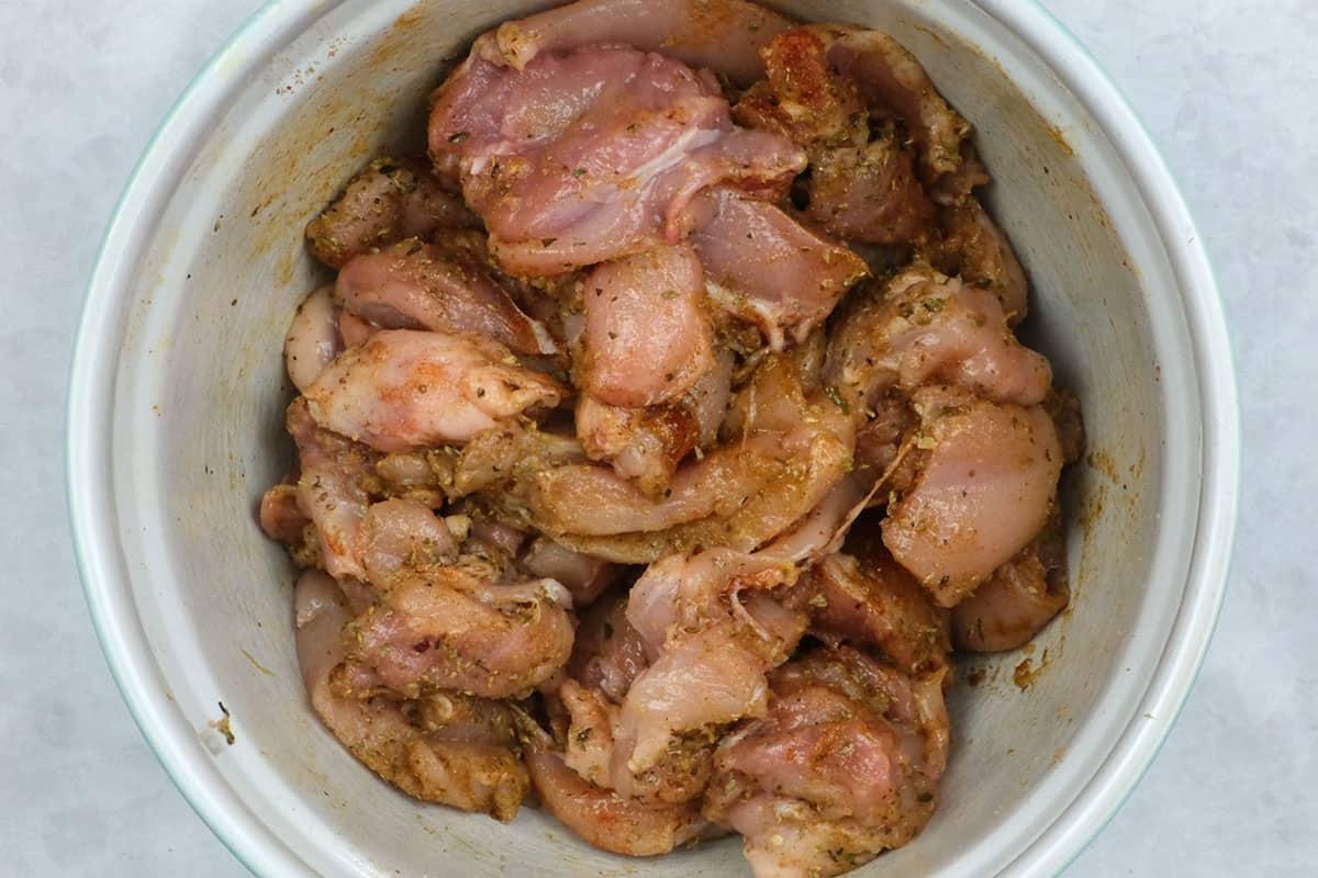chicken thighs with Greek souvlaki marinade in a bowl