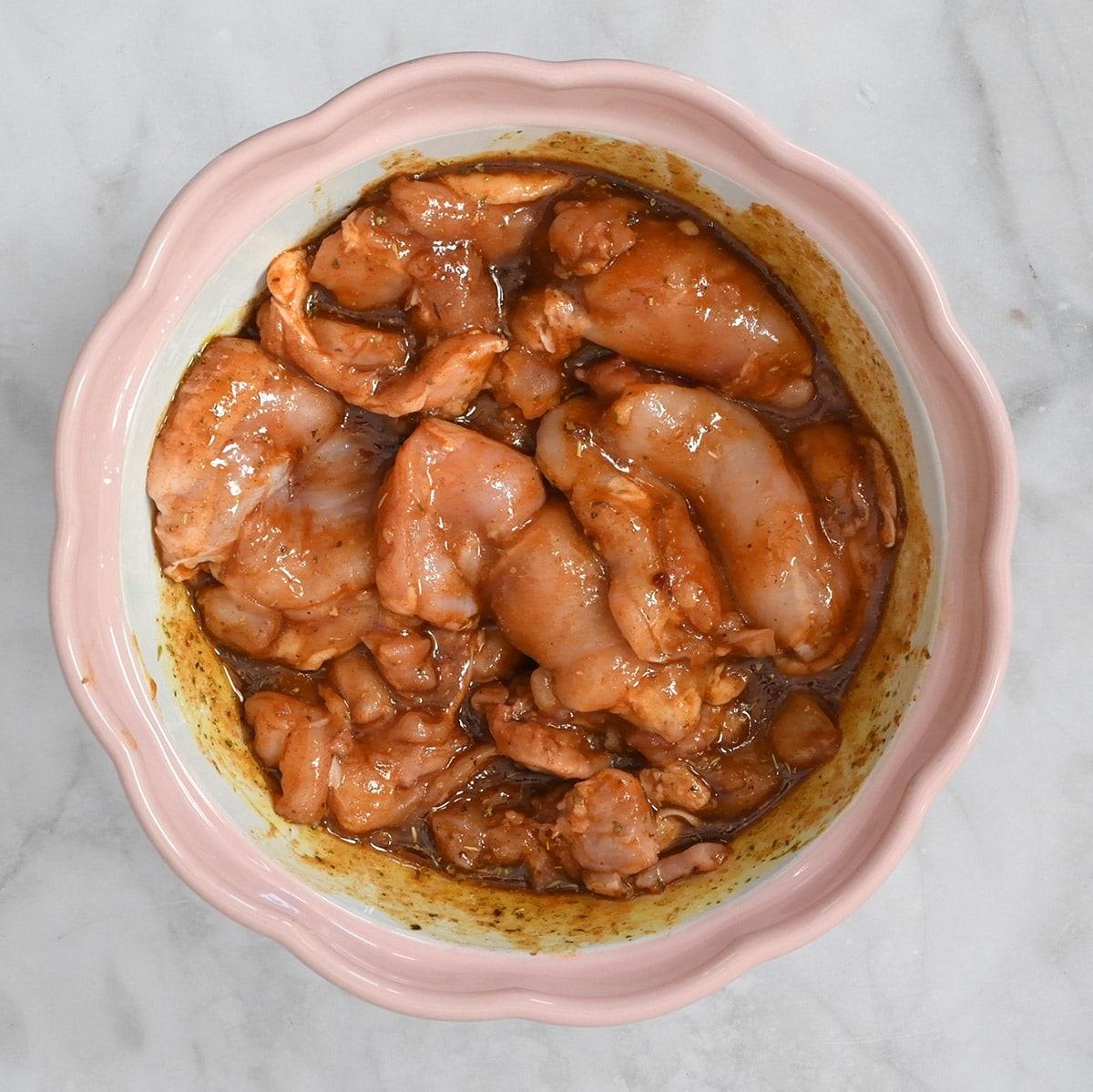 bowl of boneless skinless chicken thighs in a marinade