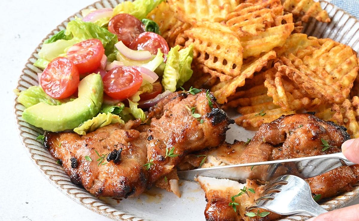 plate of crispy chicken thighs served with salad and potatoes