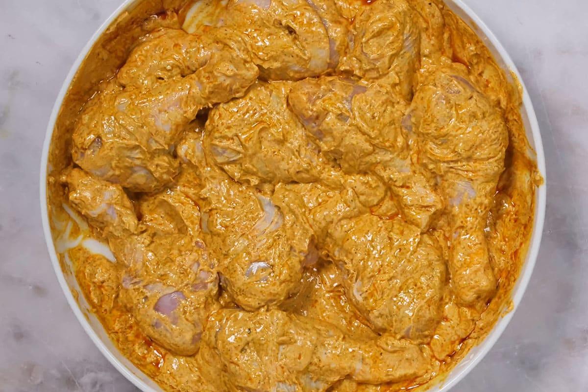 marinating tandoori chicken in spiced yogurt