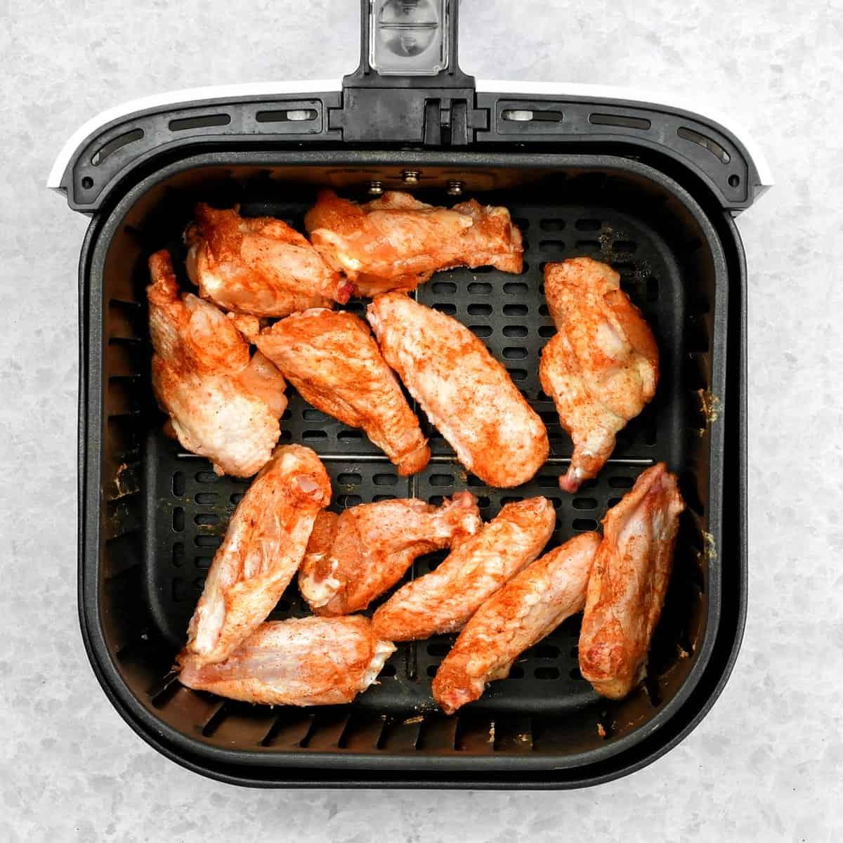 Seasoned wings in the basket of an air fryer
