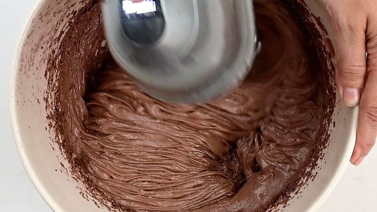 Beating batter for chocolate cake using an hand mixer