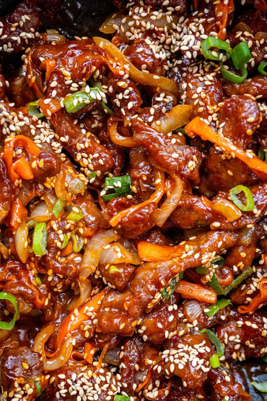 close up on Chinese crispy chilli beef garnished with sesame seeds and spring onions