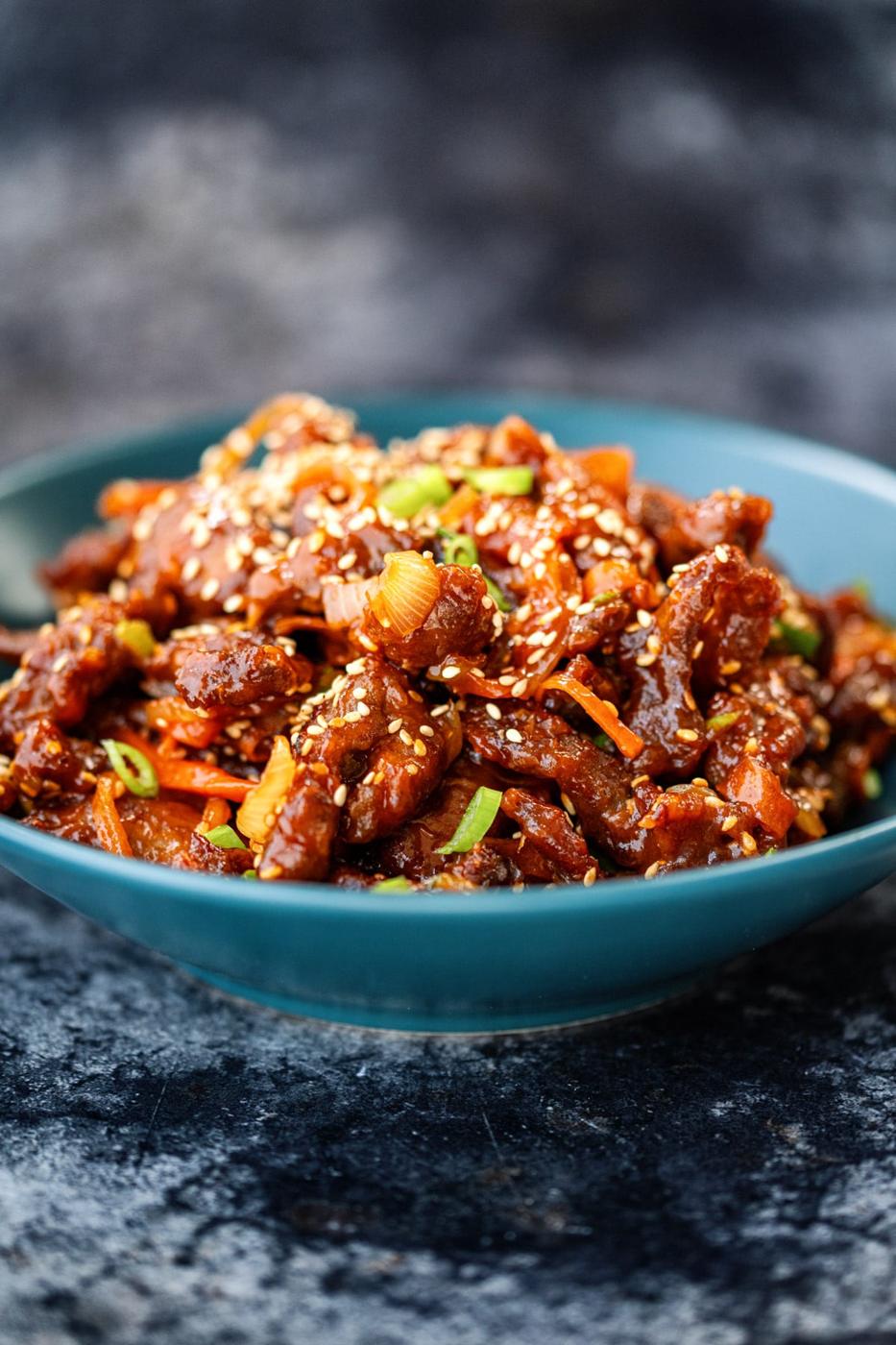 Serving of Air fryer Crispy Chilli beef in a blue bowl, side view