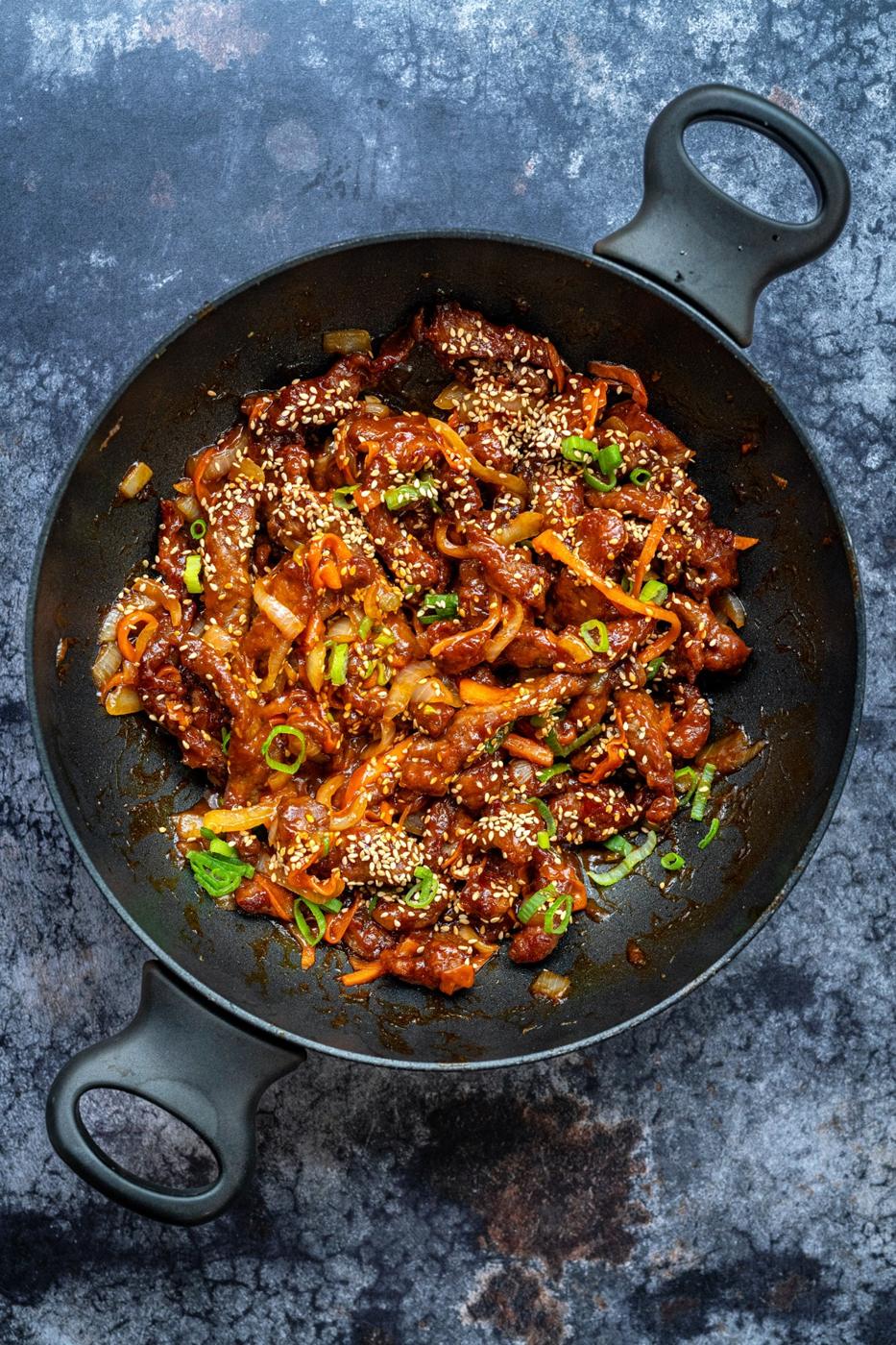 Crispy Chinese Chilli Beef in a wok against a dark background