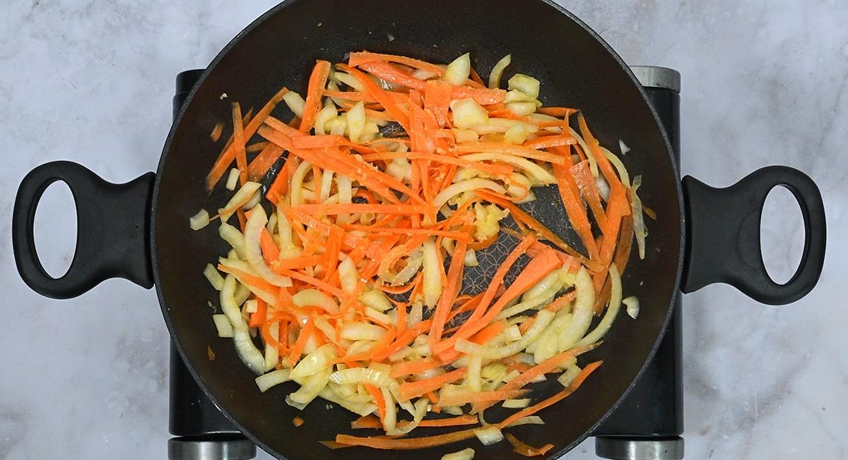 Stir frying onion, carrot strips, garlic and ginger in a wok