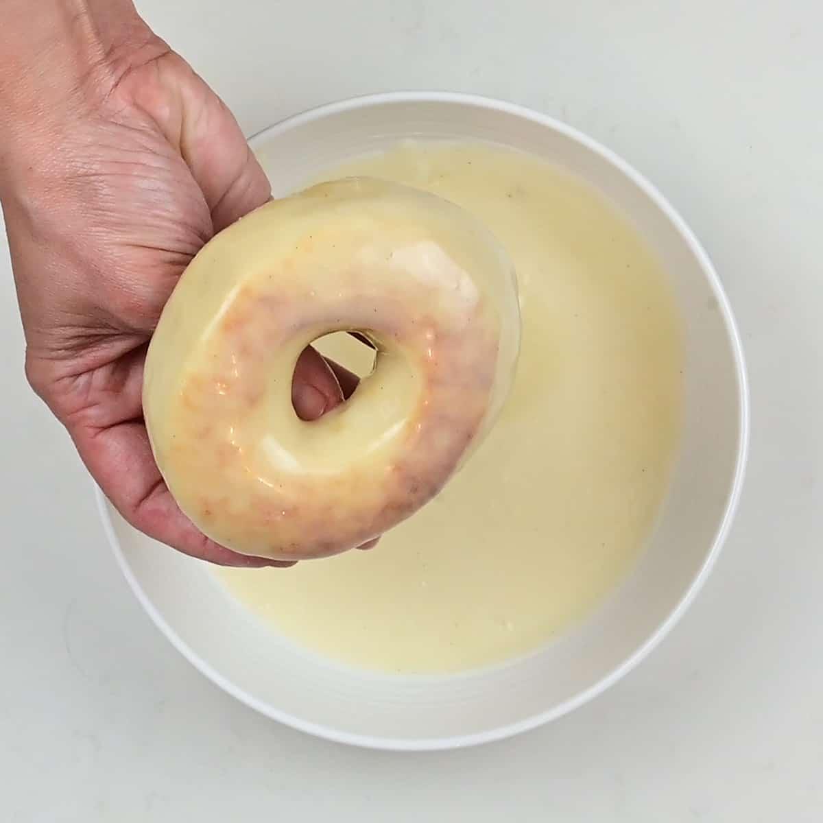 dipping air fried doughnut into glaze