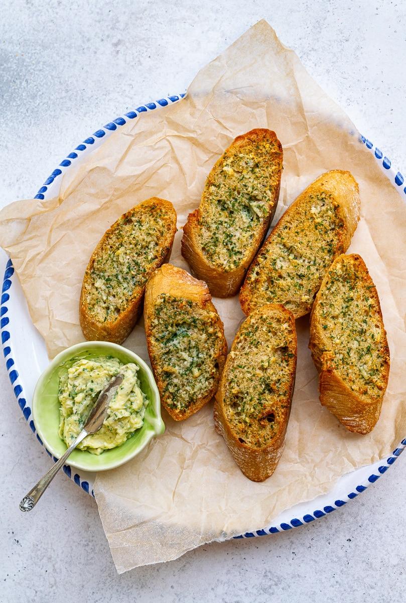 Plate of garlic bread with a side bowl of garlic butter on the side