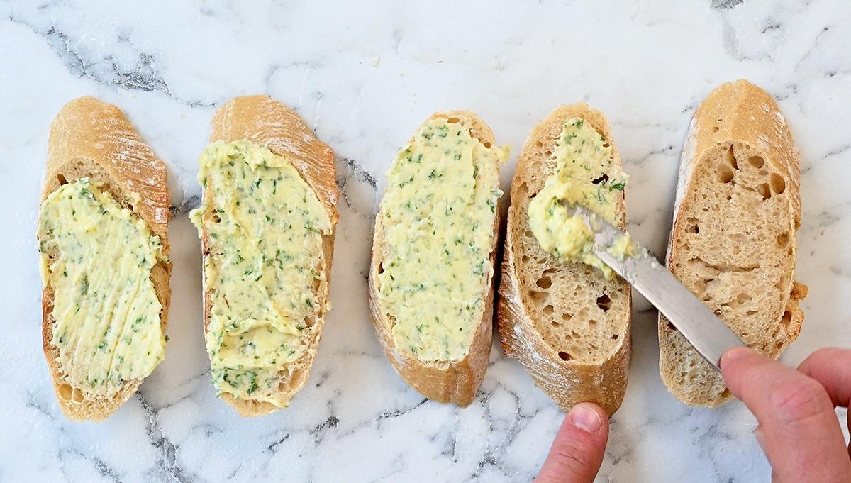 spreading slices of bread with garlic butter