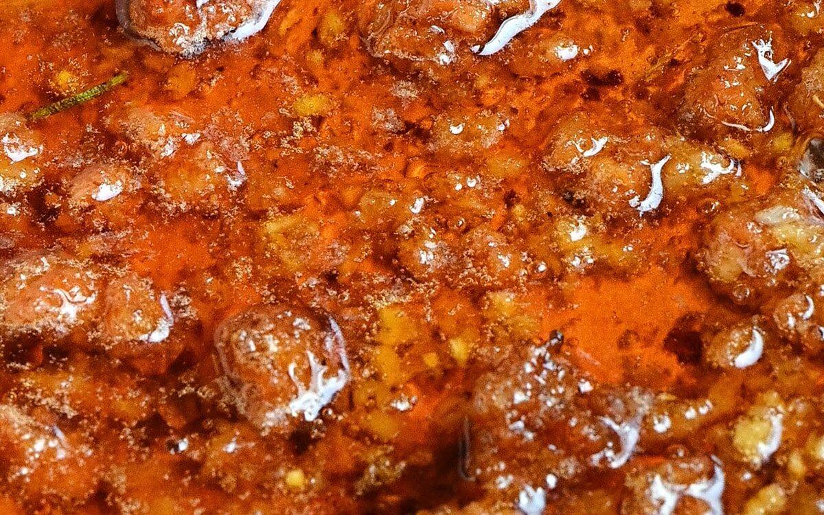 close up on sizzling oil with chorizo sausage, chili flakes, paprika