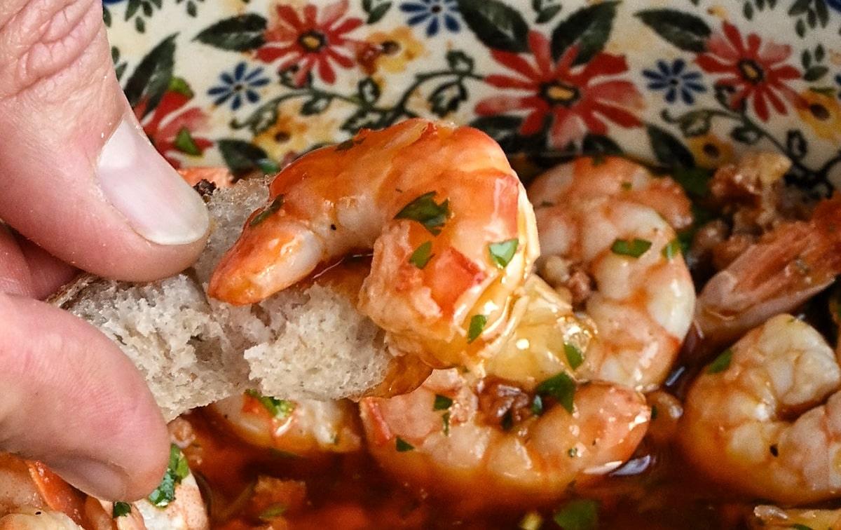 Picking up garlic shrimp with crusty piece of bread