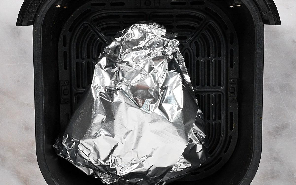 Foil-wrapped half leg of lamb in an air fryer basket