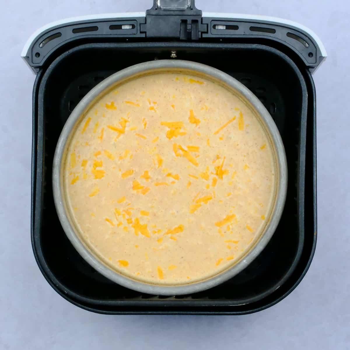 Pan with uncooked macaroni and cheese in an air fryer basket