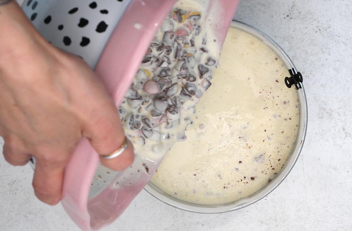 pouring cheesecake filling into a loose-bottomed cake pan
