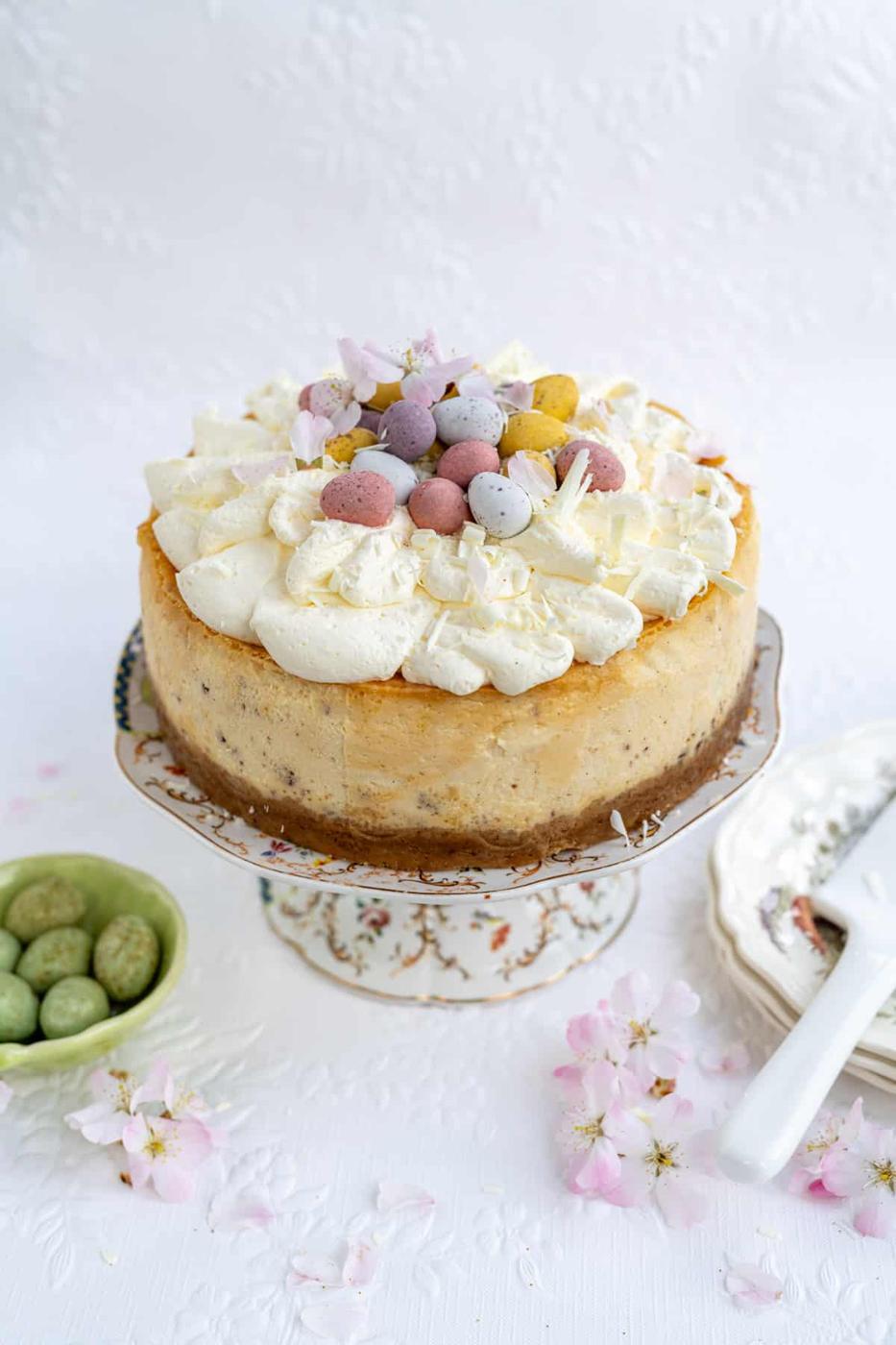Air Fryer Mini Egg cheesecake on a cake stand with mini chocolate eggs in a bowl on the side