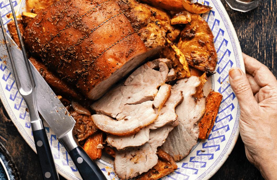 Roast pork loin on a platter with vegetables
