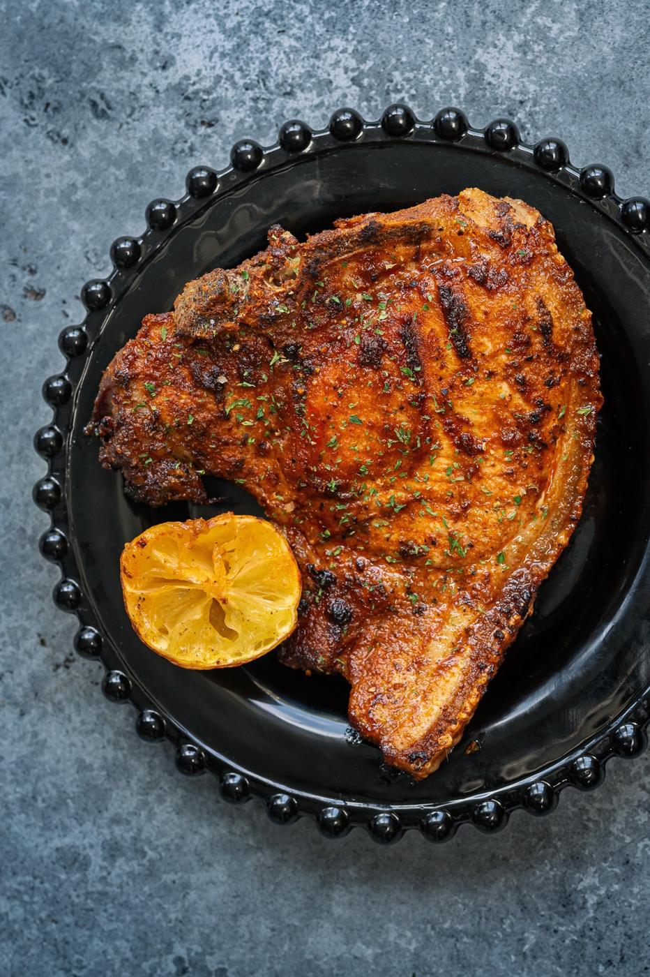 Pork chop on black plate with half a lemon