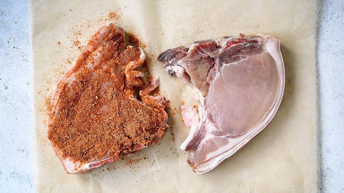 two pork chops, one covered with dry rub