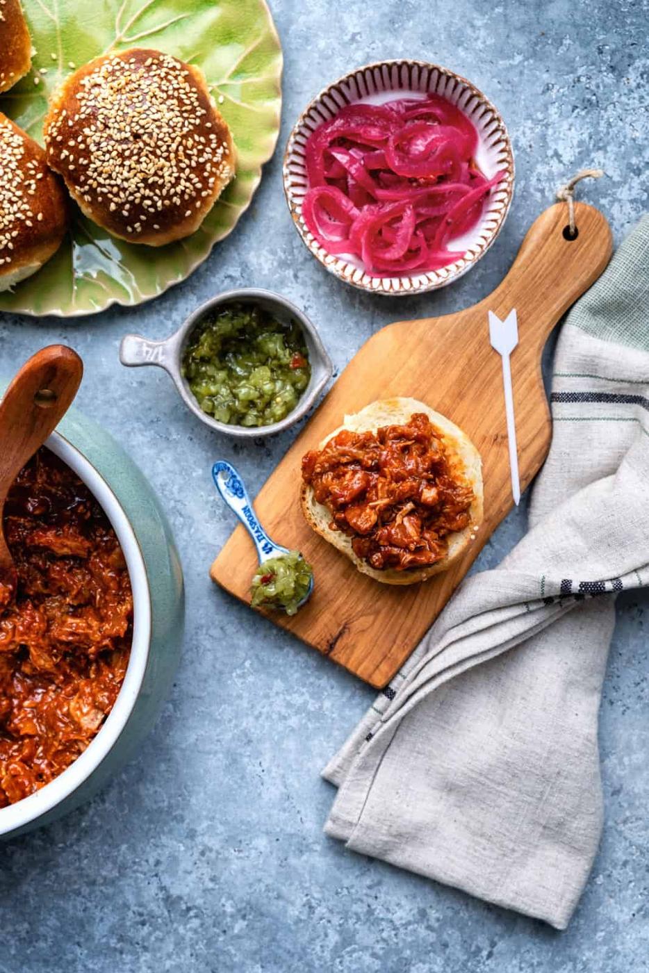 Milk bun topped with pulled pork with pickles on the side