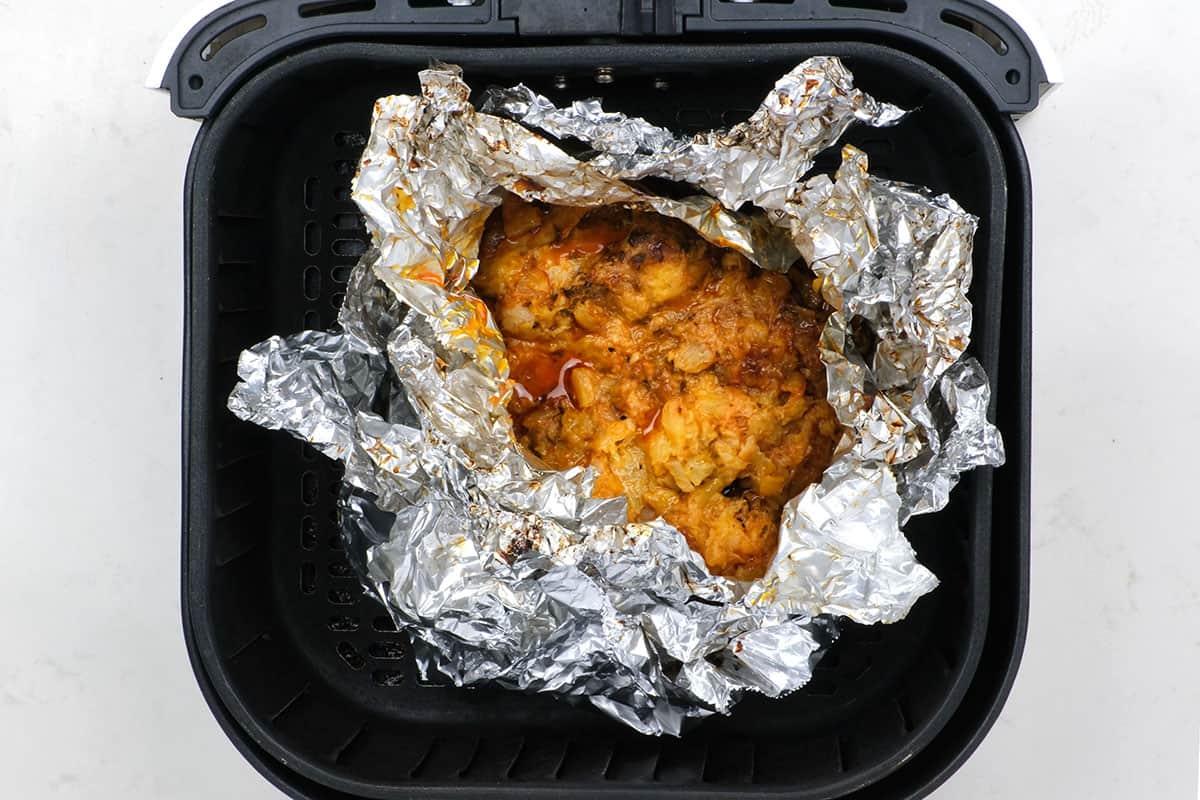 foil parcel with pork shoulder in an air fryer basket