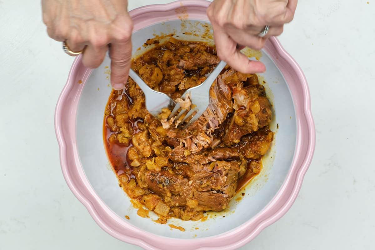 shredding cooked pork shoulder with two forks