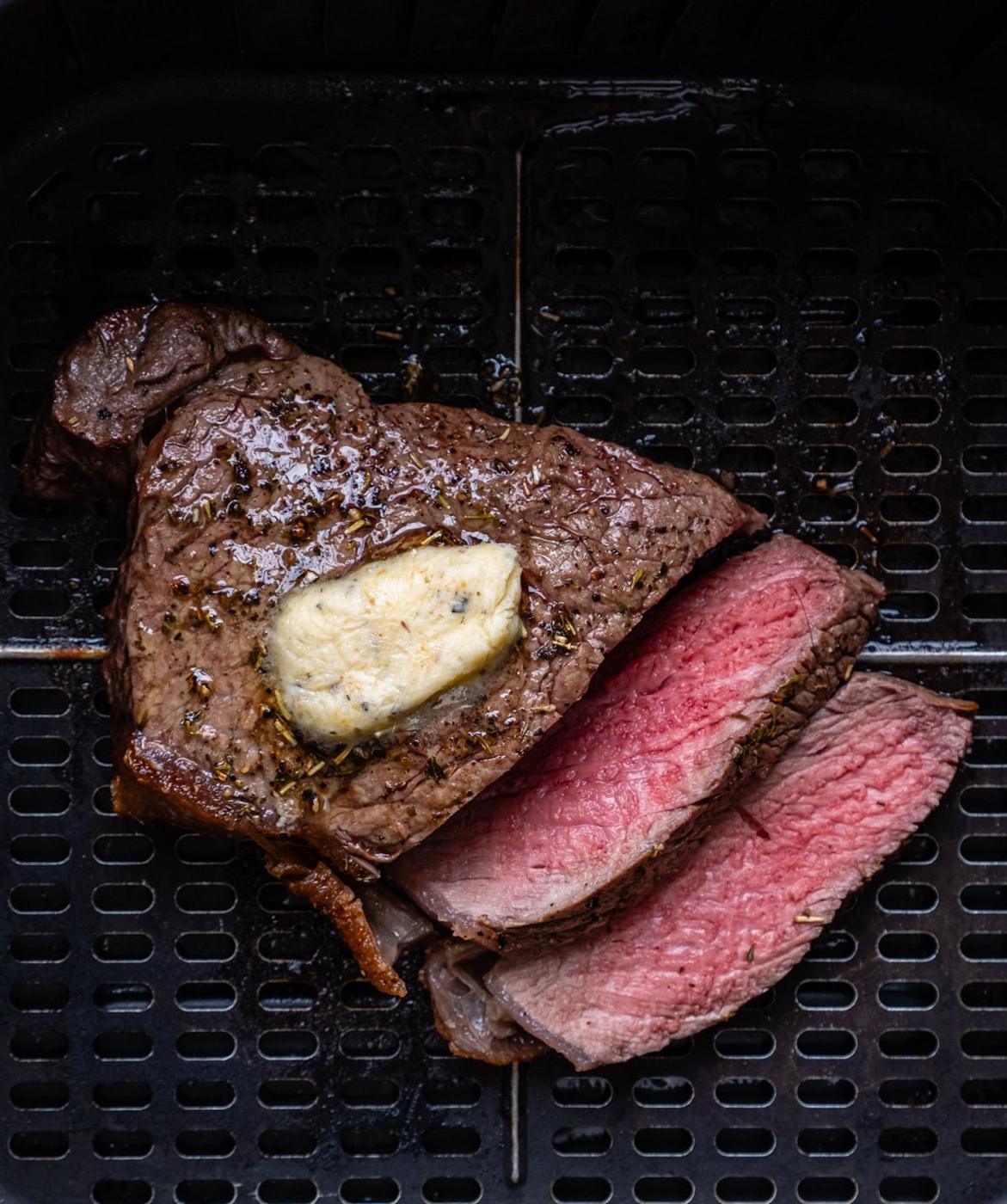 sliced rare steak topped with butter in air fryer
