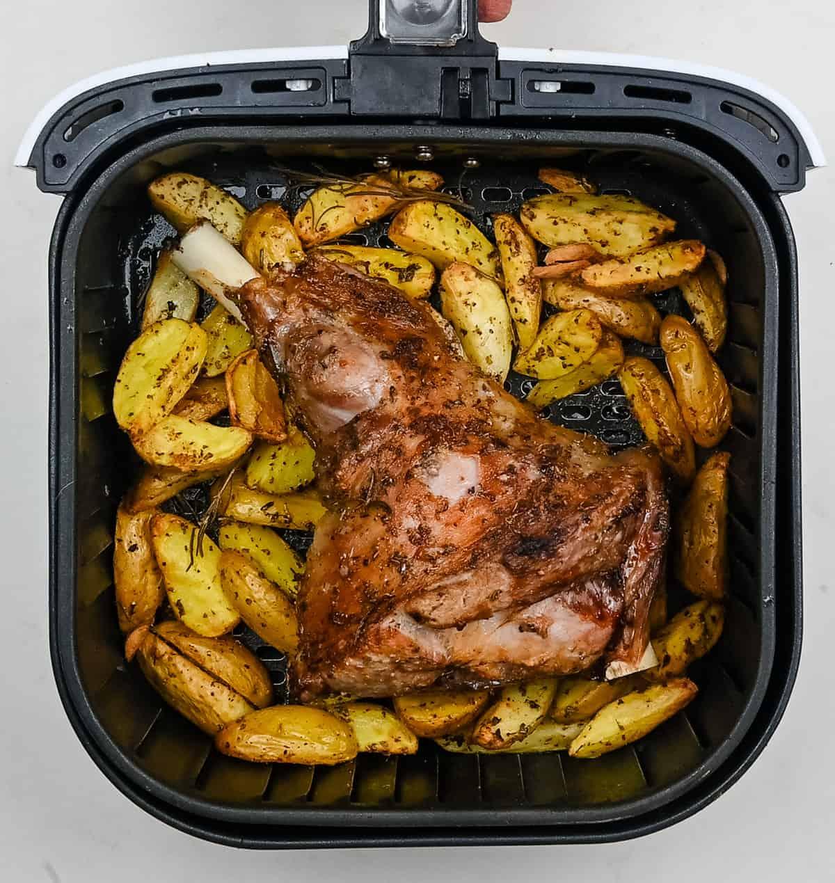 Roast half leg of lamb and potatoes in the basket of an Air Fryer