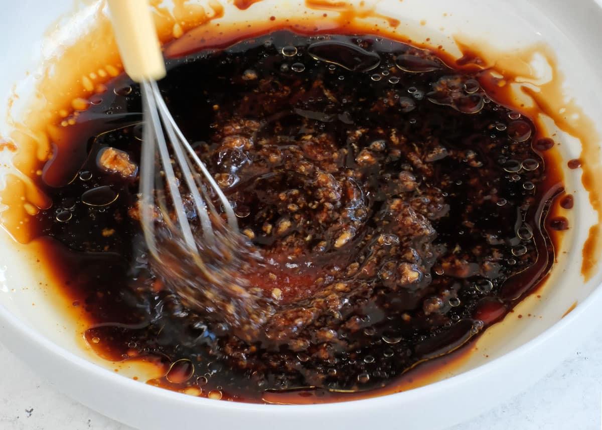 mixing marinade with a small whisk in a bowl