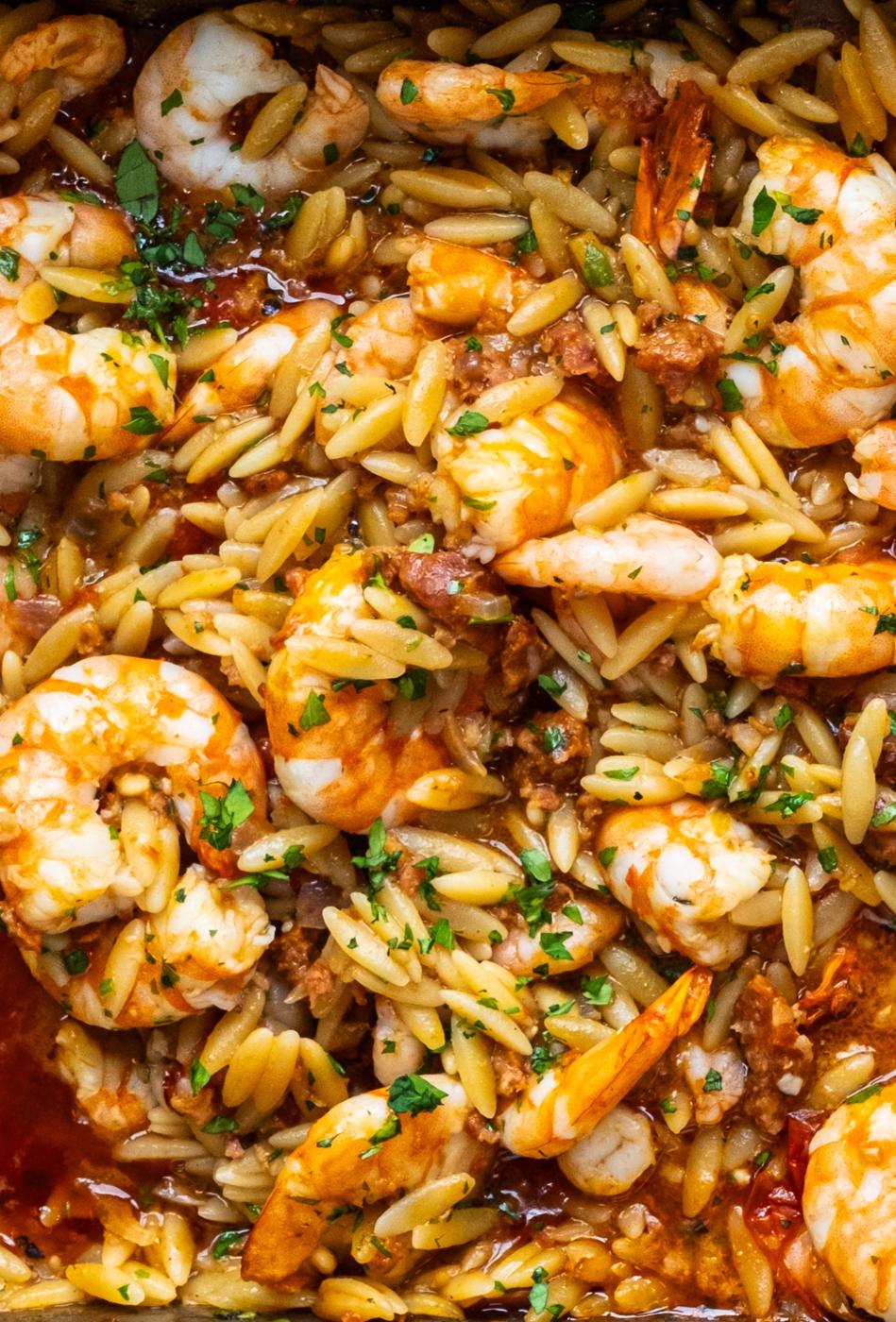 Orzo pasta mixed with shrimp, chorizo, and a savory cherry tomato-based sauce, garnished with chopped parsley—an irresistible shrimp orzo recipe.