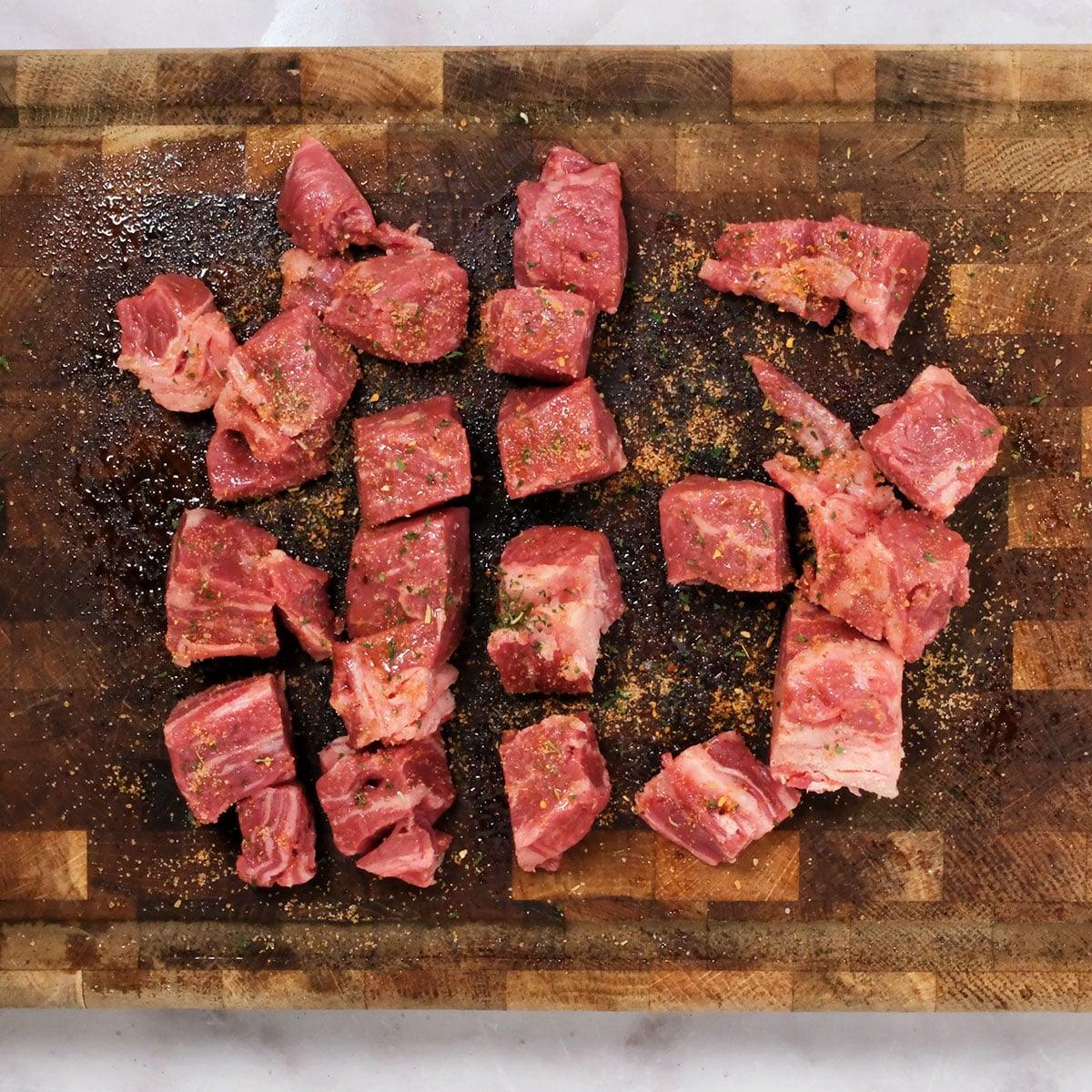 Air Fryer Steak Bites—chunks of raw beef, seasoned with spices, arranged on a wooden cutting board—promise a quick and flavorful meal.