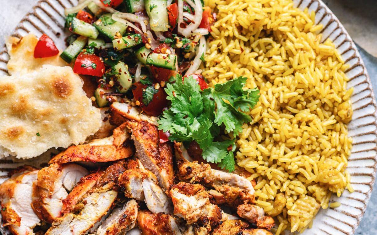 plate of tandoori chicken, rice and salad, top view