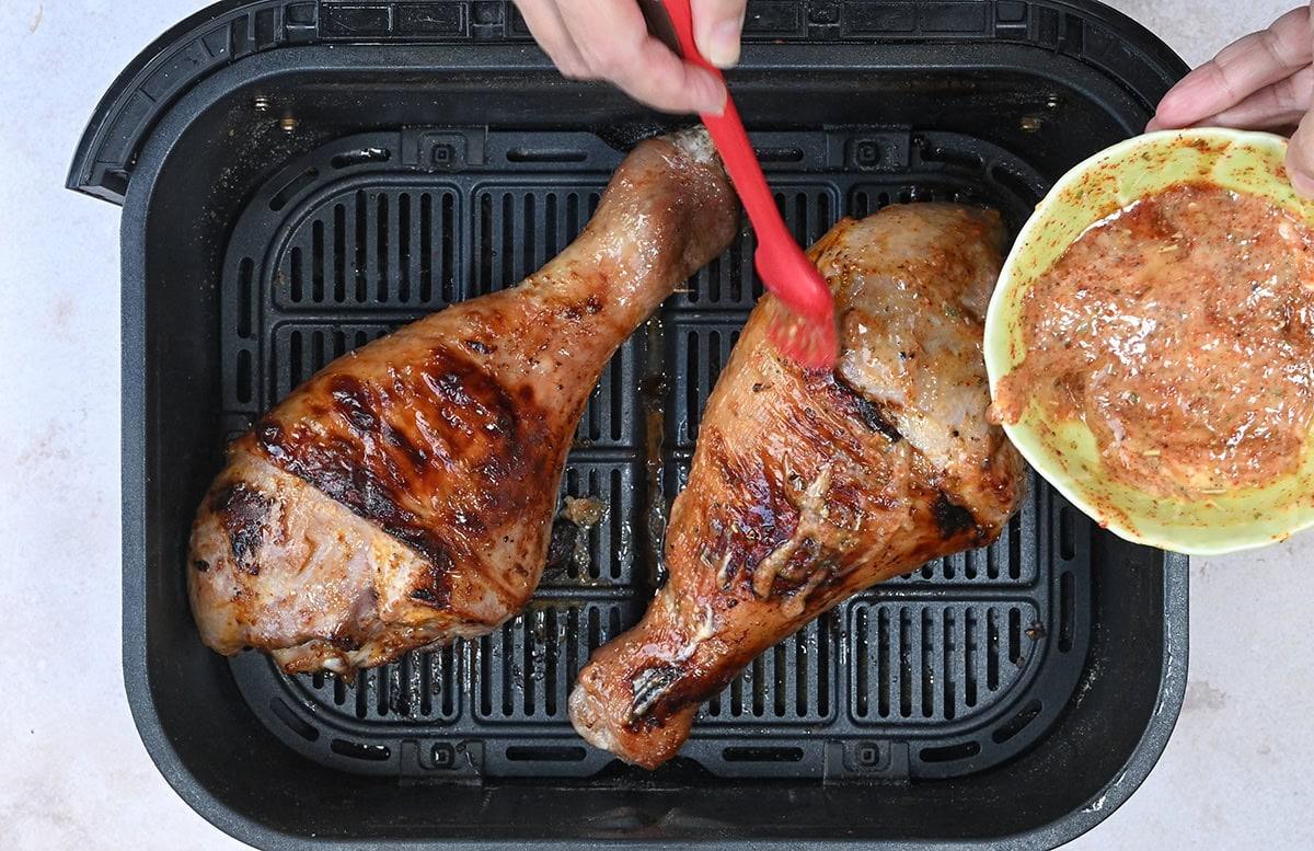 basting turkey drumsticks in an air fryer basket