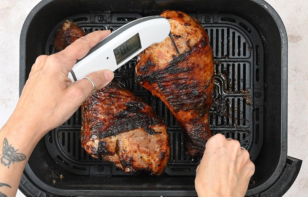 checking the temperature of turkey legs with a meat thermometer