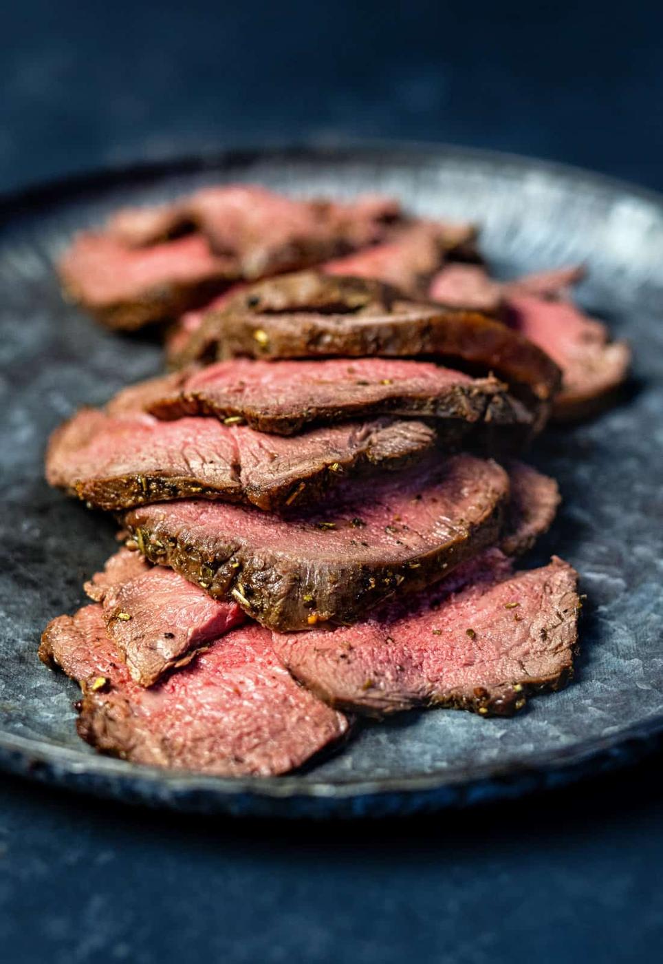 Roast venison cooked medium rare, sliced, on a plate